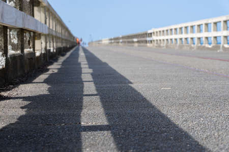 Leading lines of railings and shadows of long historic wharf, Tolaga Bay, New Zealand.の写真素材