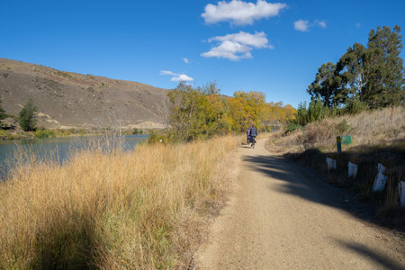 Cromwell New Zealand - April 3 2022; Cyclists on scenic Lake Dunstan track enjoying surrounds in autumn colours at Cromwell South Island New Zealand.のeditorial素材