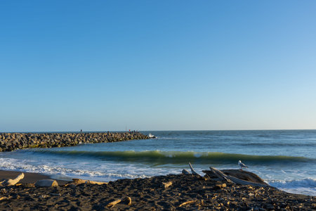 Whanganui New Zealand - April 9 2022; Beach at Castlecliff with rock groyne breakwater projecting...
