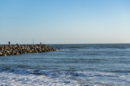 Whanganui New Zealand - April 9 2022; Beach at Castlecliff with rock groyne breakwater projecting into sea with fishersのeditorial素材