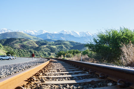 Kaikoura New Zealand - May 11 2022; Rusty rail tracks running along Kaikoura coast with man walking away.のeditorial素材