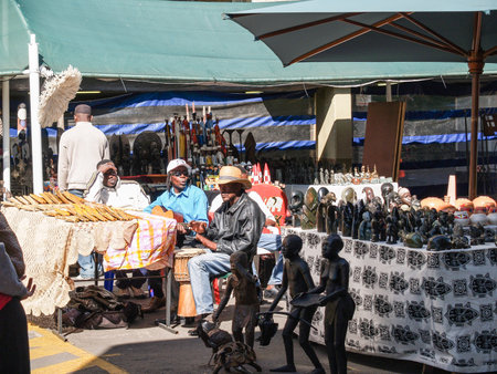 Johannesburg South Africa - August 12 2027; African men sitting at sales table in city craft market selling carved figures to tourists.のeditorial素材