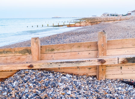 Worthing beach wooden breakwater leading into sea over stony beach at sunrise United Kingdom.の写真素材
