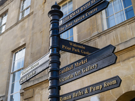 Bath United Kingdom - June 18 2009; Bath street lined by buildings leading to trees and hill with tower 2009; Sign pointing towards important city tourist attractionsのeditorial素材