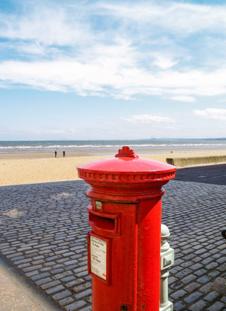 Traditional red pillbox, or British post box at Portobello by beach, Scotland.