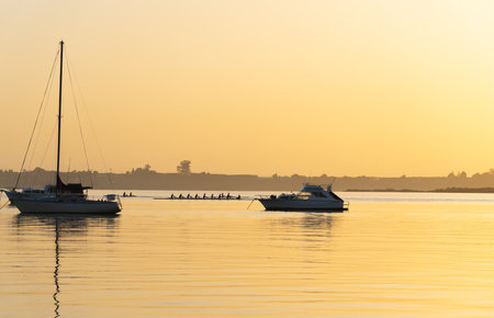 Golden hues of Tauranga Downtown waterfront sunrise over calm harbour waterの写真素材