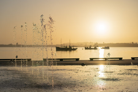 Focus on-water fountain spurts water in air against golden hue of sunrise on Tauranga Downtown waterfrontの写真素材