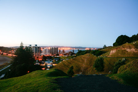 As sunrises while lights still on in town from slope on Mount Maunganui, Tauranga New Zealand.の写真素材