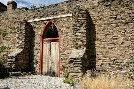 Clyde New Zealand - February 27 2010; Old stone exterior wall and door of rustic historic building  in street in Clyde in South Islandの写真素材