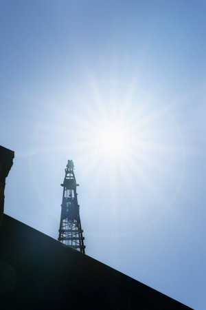 Construction crane back-lit and topped by sun star-burst over building site.の写真素材