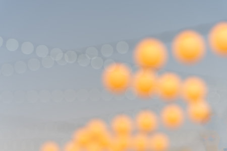 Round orange coloured spheres in abstract defocused pattern overhead against blue sky.の写真素材
