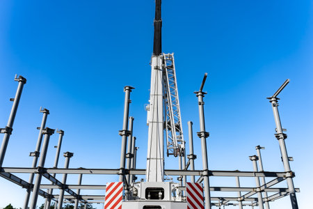 Construction crane towering over structural steel framing for new building under blue sky.