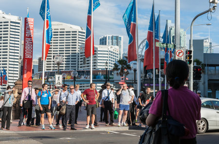 Sydney Australia - January 25 2011; People waiting standing on curb in variety of dress at crossing  city street to Pyrmont Bridge on Darling Harbour.のeditorial素材