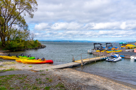 Taupo New Zealand - April 15 2023; Lake Taupo water's edge with jetty and hire kayaks and boats.のeditorial素材