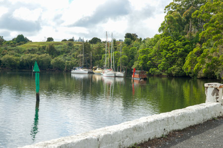 Yachts and houseboat moored behind red and green channel marker in bay surrounded by green trees at Paihia.の写真素材