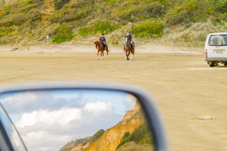 Bayleys Beach New Zealand March 6 2011; two horses and riders on beach with dunes reflected in car rear vision mirror.の写真素材