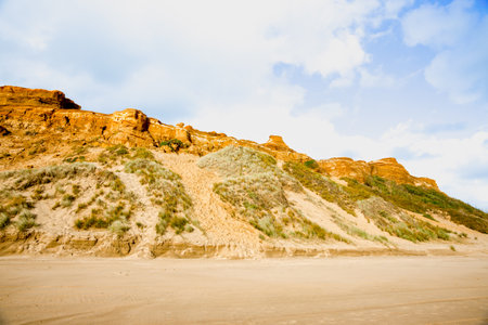 Orange coloured sand dunes and beach at Bayleys beach in Northland New Zealand.の写真素材