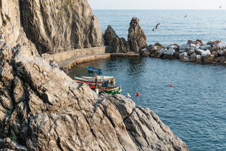 Manarola Italy - April 25 2011; Sheer rock face and seawall or breakwater making small boat harbour...