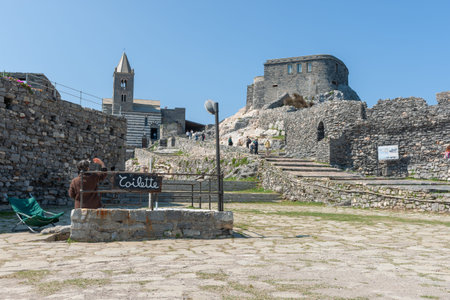 Portovenere Italy - April 27 2011; Sign for Toilette below medieval stone ruins and Church of Saint Peters in 12th century Italian town,のeditorial素材