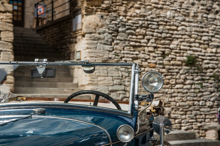 Gordes, France - May 1 2011; Vintage blue car windscreen and lights in close-up parked in front historic stone building in picturesque French hilltop walled town.のeditorial素材