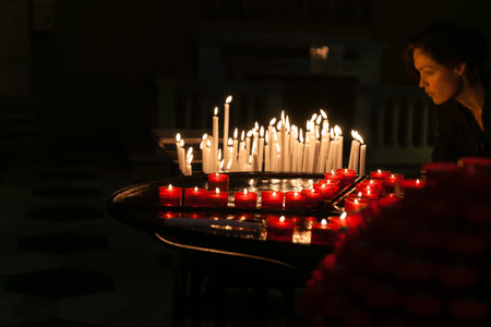 Como Italy - May 6 2011; Illuminated face or woman looking at group of prayer candles.のeditorial素材