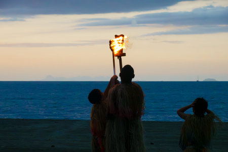 Denarau Fiji - September 3 2023; Lighting the flame at dusk local Fijian man and boys in silhouetteのeditorial素材