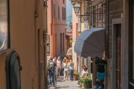 Bellagio Italy - May 8 2011; people  in sunny gap between buildings in Italian street scene in typical tourist destination.のeditorial素材