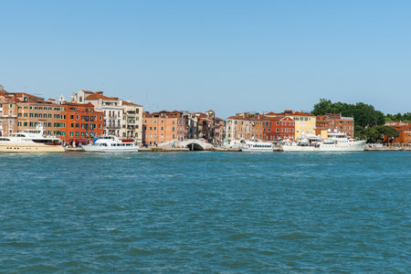 Venice Italy - May 10 2011; Arched bridge over canal between typical buildings and boats on Grand Canal waterfront.のeditorial素材
