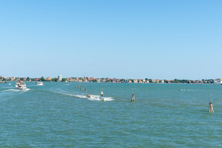 Venice Italy - May 10 2011; Channel markers leading between islands of Venice with boats and ferries providing transport and dome of Santa Maria Elisabetta church in Lidoのeditorial素材