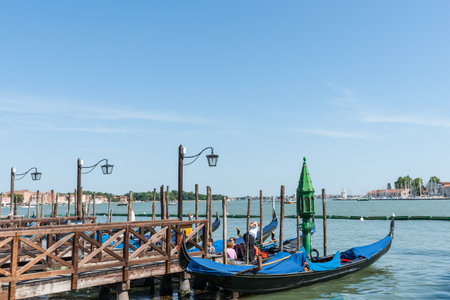 Venice Italy May 11 2011; Gondola alongside pier with tourists and wide view of water and sea around famous tourist destination.のeditorial素材