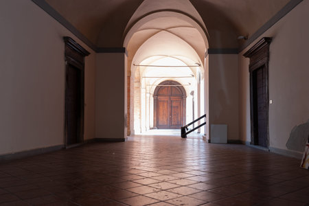 Gubbio Italy - May 12 2011; Daylight illuminates rear portion of empty hallway with tiled floor and...