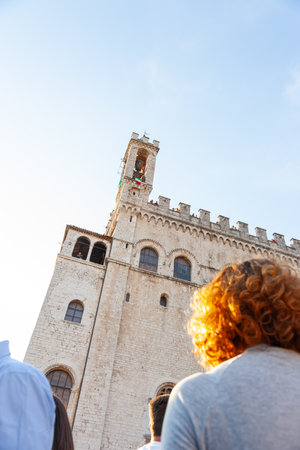 Gubbio Umbria, Italy-May 15 2011; Late afternoon in European town square as bell-rings from high tower for crowd below.のeditorial素材
