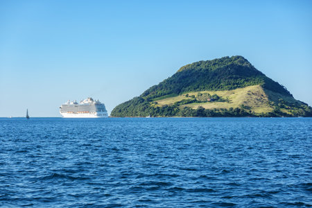 Tauranga New Zealand- March 76 2024; Large cruise ship in and leaving Tauranga harbour with icon landmark Mount Maunganui on horizon.のeditorial素材