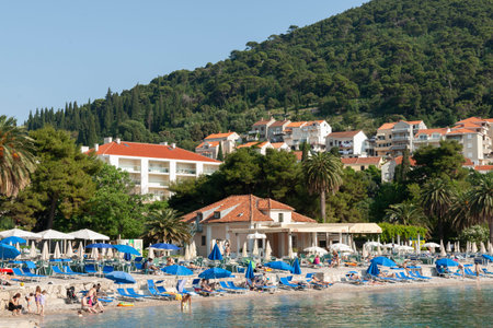 Dubrovnik Croatia - May 29 2011; Editorial-Crowded Uvala Lapad beach with people and blue umbrella.のeditorial素材