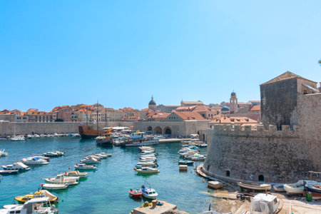 Dubrovnik Croatia - May 28 2011; Picturesque harbour and marina with old town walls and modern orange rooftop skyline under. blue sky.のeditorial素材