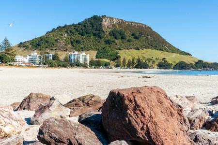 Landmark tourist destination  Mount Maunganui standing at end of Main beach with foreground rocksの写真素材