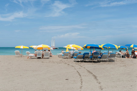 Miami Florida America - June 28 2012; People on beach with yellow and blue umbrella on summer day.のeditorial素材