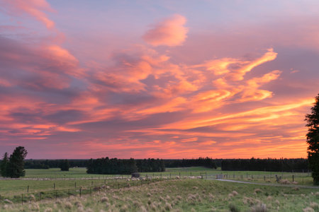 Dramatic bright colourful sunset sky over silhouette rural landscape in South Island New Zealand.の写真素材