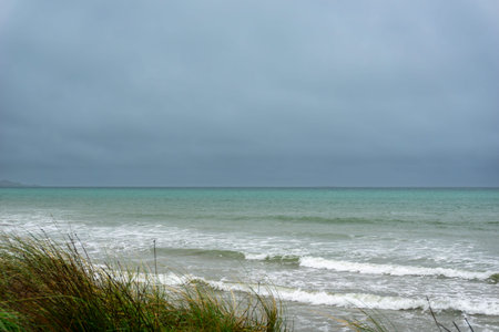 Windy overcast day with view out to horizon at Colac Bay in southern New Zealand coastal background.