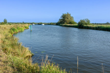 Norfolk Broads river cruising along Bure River through flat green tranquil landscape