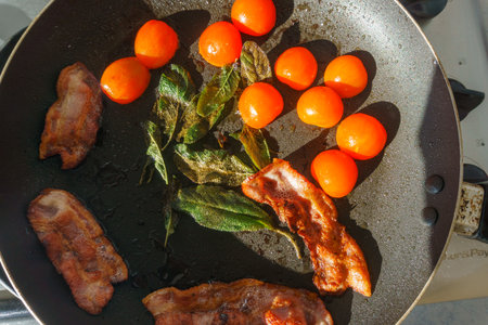 Basic breakfast food ingredients in frying pan cooking outdoors in sun.の写真素材