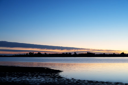 Tauranga sunrise during blue hour across Waimapu estuary long cloud and blue sky over silhouette...