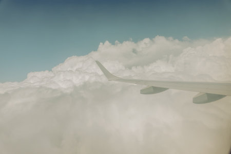 Through plane window blue sky and white cloud background image with white plane wing in vintage effect.の写真素材