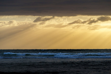 Dark cloudy sky and sea separated by golden hour moody sky at Lennox Heads New South Wales...
