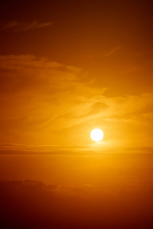 Golden sky across sea with round glowing sun just above horizon.in vertical composition at Lennox...