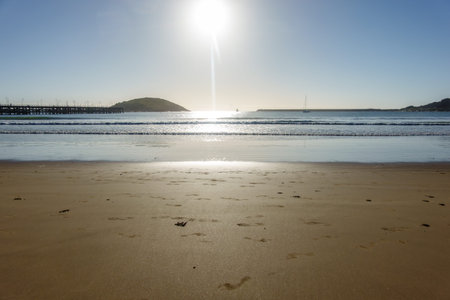 Coffs Harbour from beach between pier and Corambirra  Point as sun flares low in sky above horizon New South Wales Australia.の写真素材