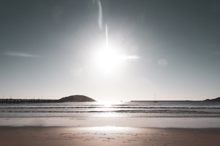Coffs Harbour from beach between pier and Corambirra  Point as sun flares low in sky above horizon New South Wales Australia.の写真素材