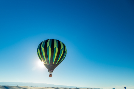 Colorful hot air balloons fly over the glistening gypsum dunes at White Sands National Monument during the 2016 Balloon Invitational.の写真素材