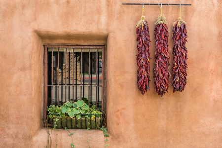 A ristra is an arrangement of drying chile pepper pods, garlic bulbs, or other vegetables for later consumption. In addition to its practical use, the ristra has come to be a trademark of decorative design in the state of New Mexico.の写真素材