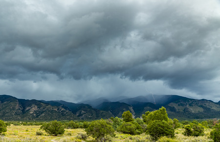 A lightning strike highlights an afternoon thunderstorm along North Zapata Ridge in the Sangre de Cristo Mountain Range of the southern Rocky Mountains.の写真素材